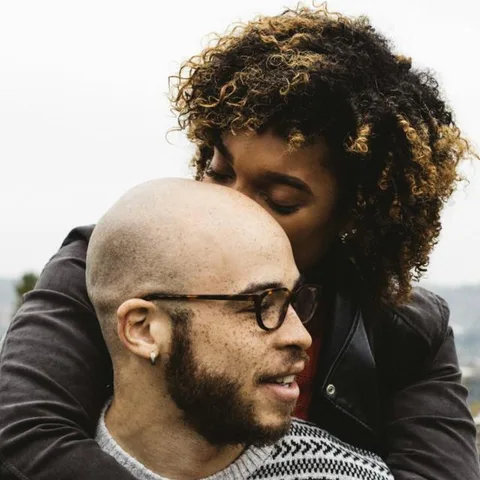 Pareja abrazada, ella le besa la frente a él